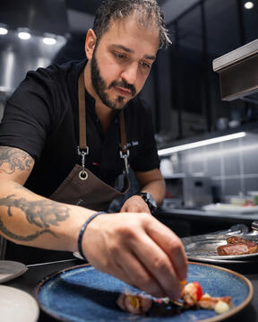 Chef George Tanos plating a dish during service in a professional kitchen